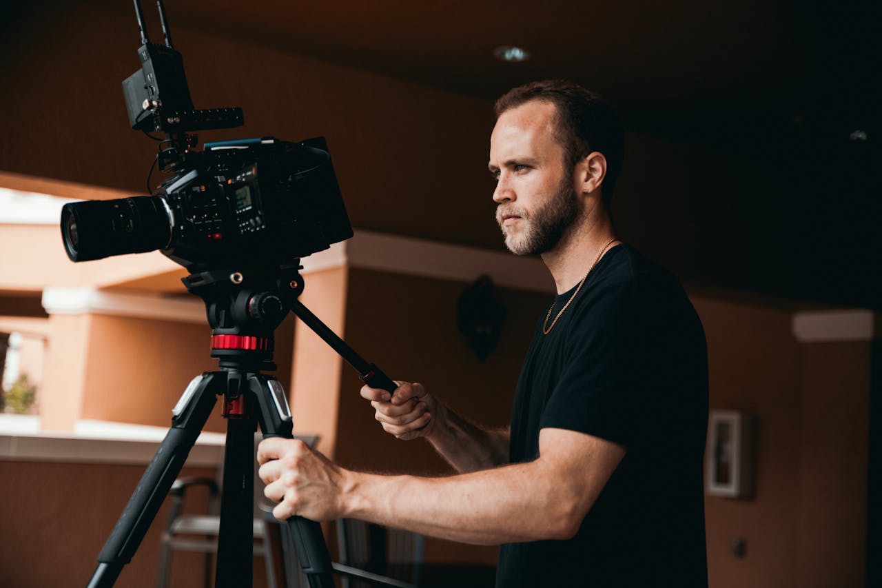 Professional cameraman adjusting camera on tripod in a studio setting.