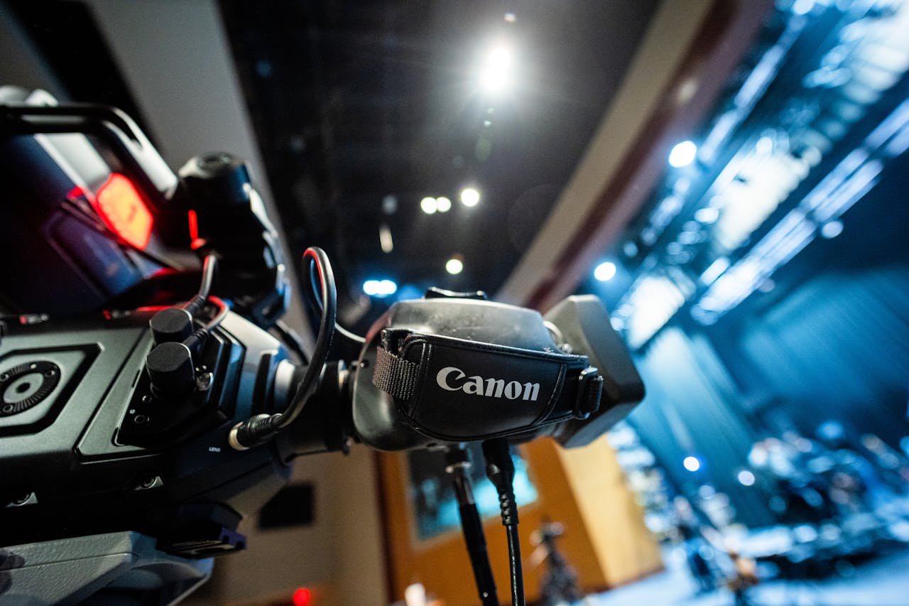 Professional video camera focusing on stage lighting setup in a modern hall.
